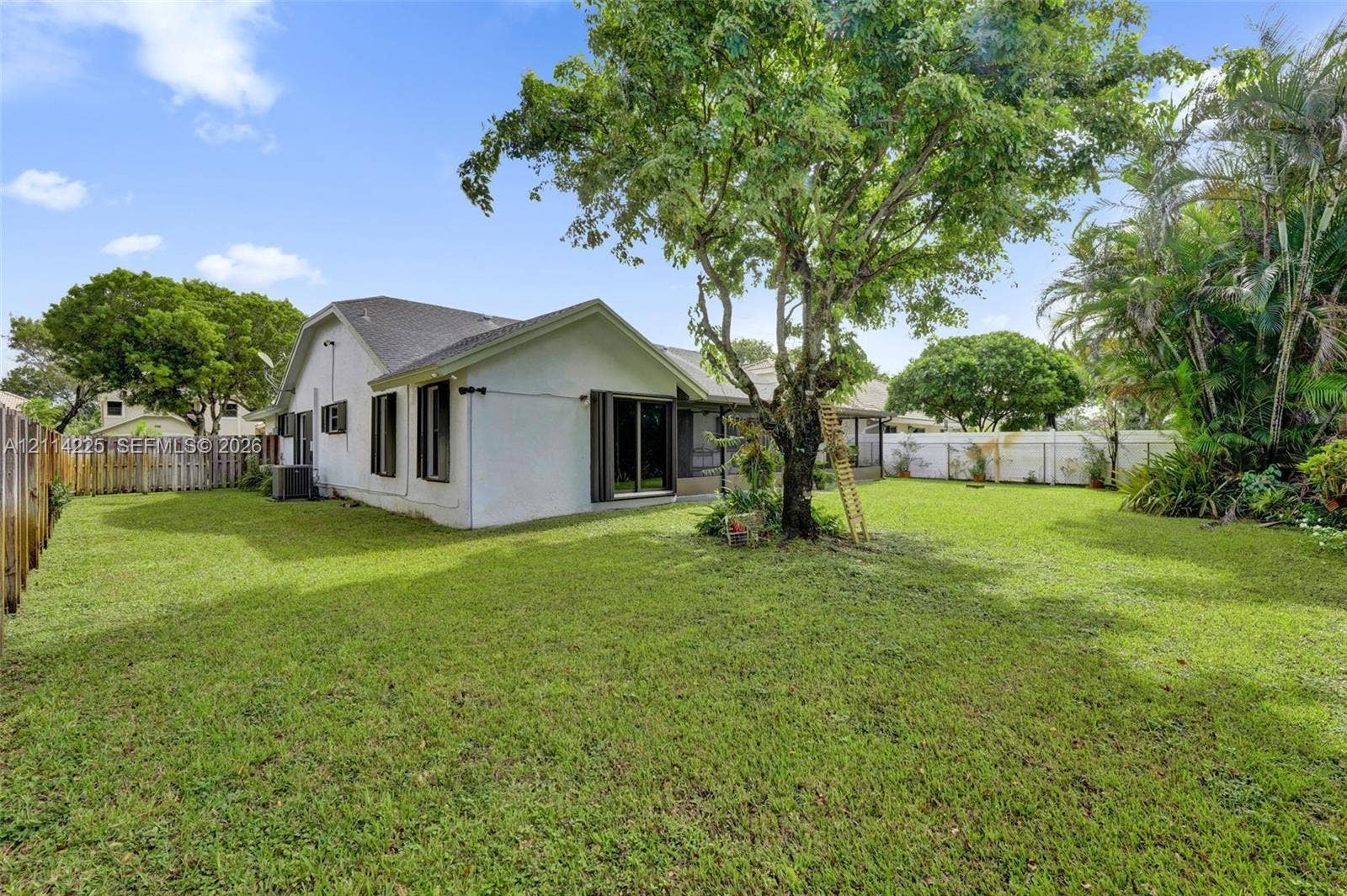 5741 SW 88th Terrace, Cooper City, FL 33328 Expansive backyard featuring a mature canopy tree, perimeter wood fencing, white vinyl privacy screening, and low-maintenance landscaping