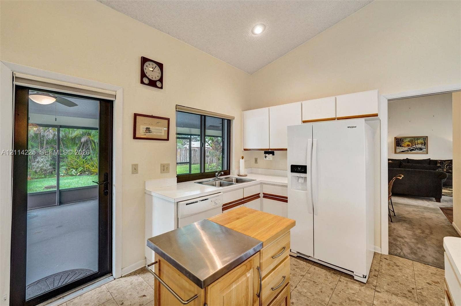 5741 SW 88th Terrace, Cooper City, FL 33328 Kitchen featuring white cabinetry, solid-surface countertops, double-basin sink, and tile flooring, with an integrated glass door providing outdoor access