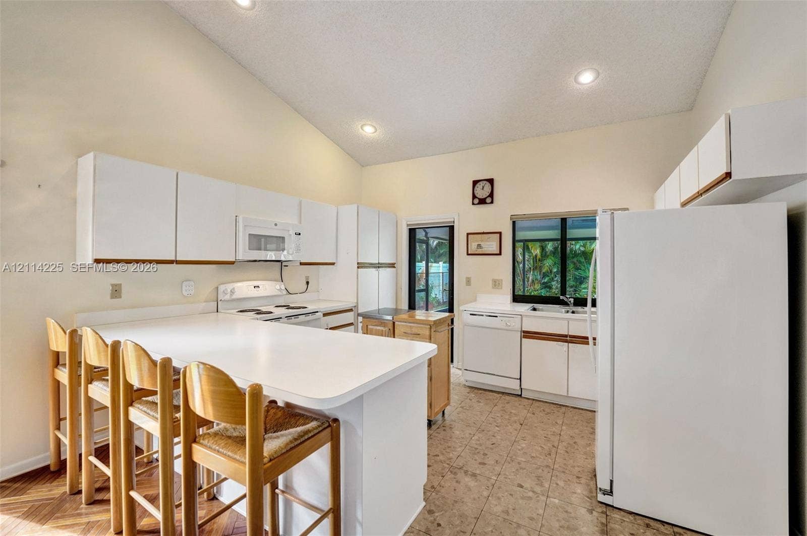 5741 SW 88th Terrace, Cooper City, FL 33328 Kitchen featuring a vaulted ceiling, recessed lighting, white cabinetry, a breakfast bar, and tile flooring