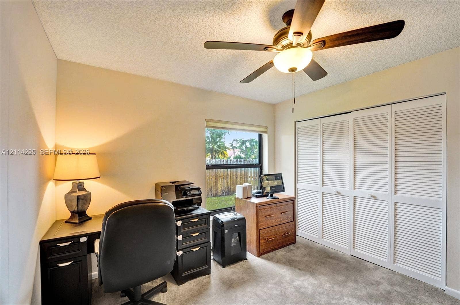 5741 SW 88th Terrace, Cooper City, FL 33328 Room featuring a textured ceiling, a four-blade ceiling fan with an integrated light fixture, and white louvered closet doors