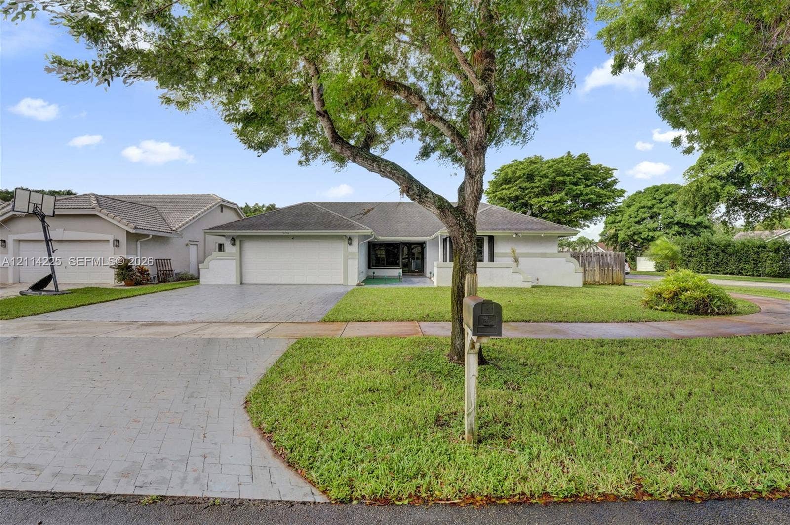 5741 SW 88th Terrace, Cooper City, FL 33328 Single-story residence featuring a tile roof, paved driveway, two-car garage, and established landscaping