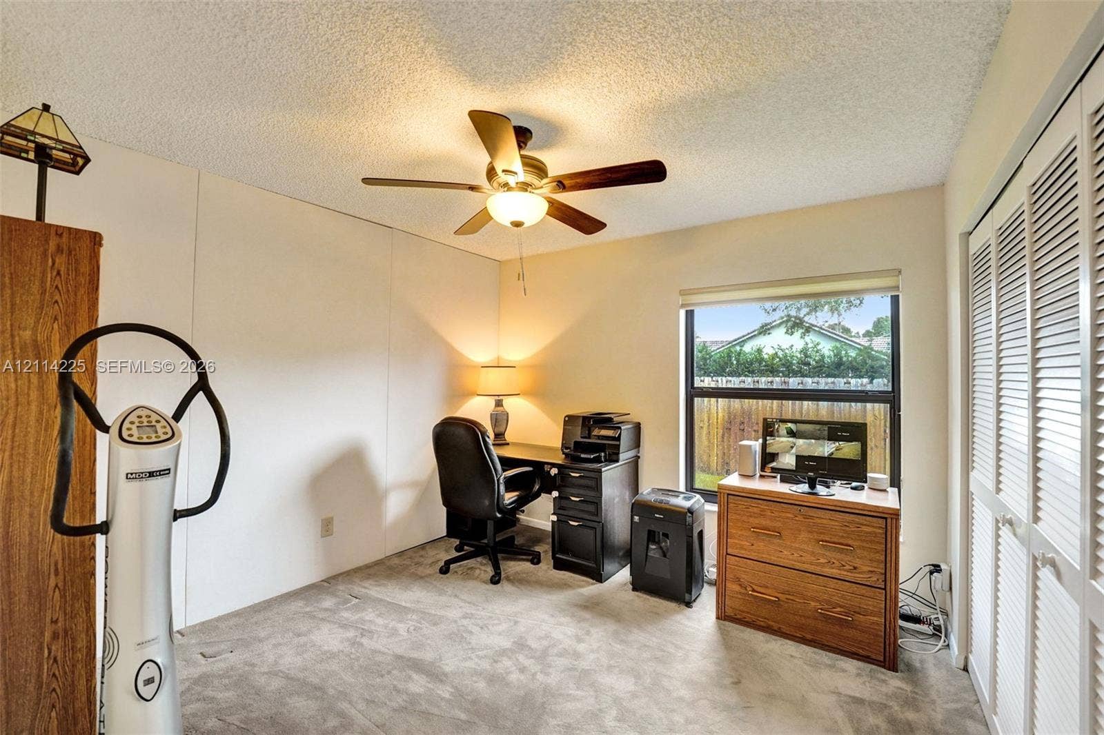 5741 SW 88th Terrace, Cooper City, FL 33328 Room featuring neutral carpeted flooring, a ceiling fan with integrated light fixture, and floor-to-ceiling closet with louvered doors