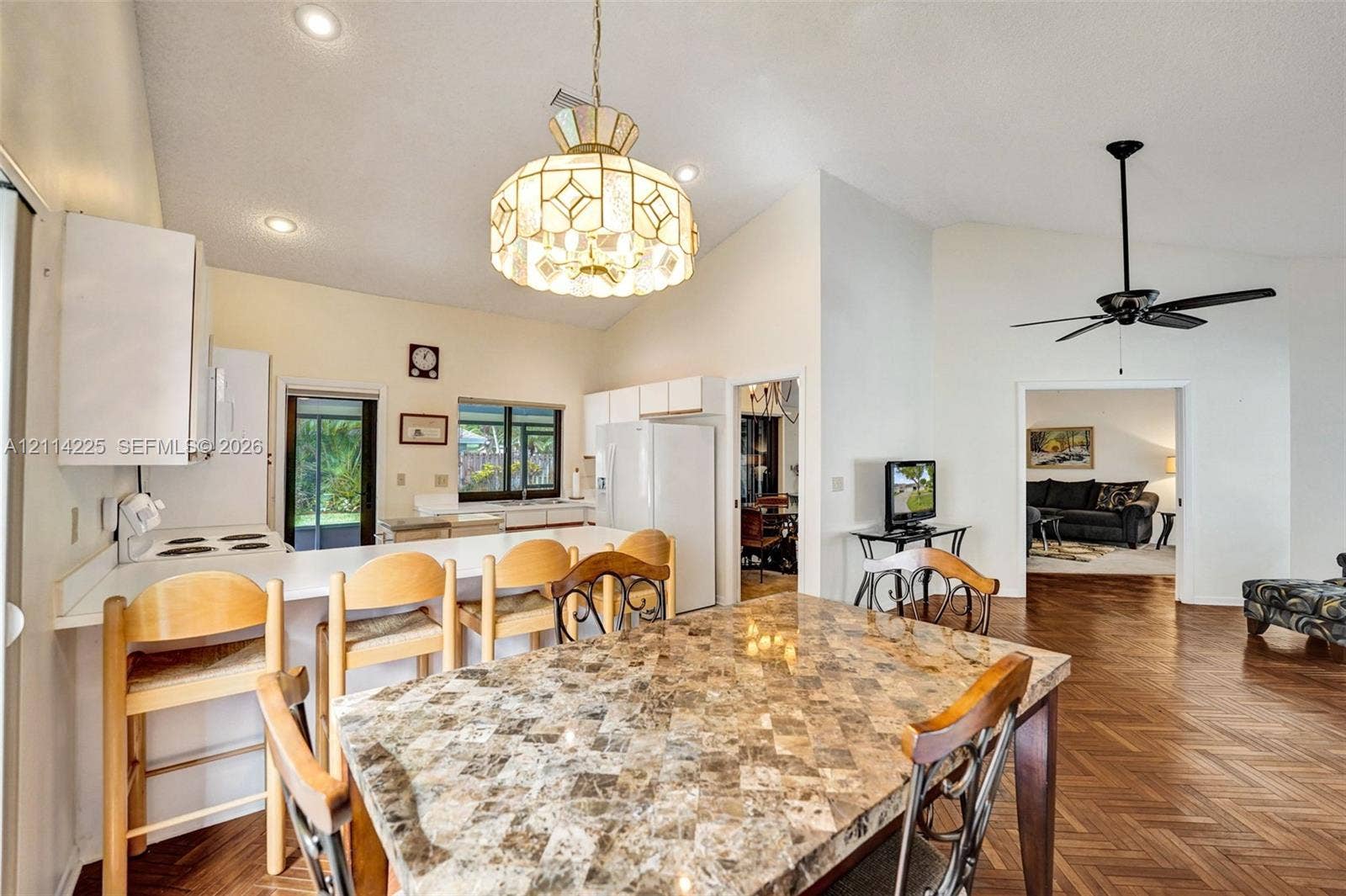 5741 SW 88th Terrace, Cooper City, FL 33328 Open-concept kitchen area featuring vaulted ceilings, recessed lighting, a decorative pendant light fixture, wood-finish flooring, and a stone-topped breakfast bar