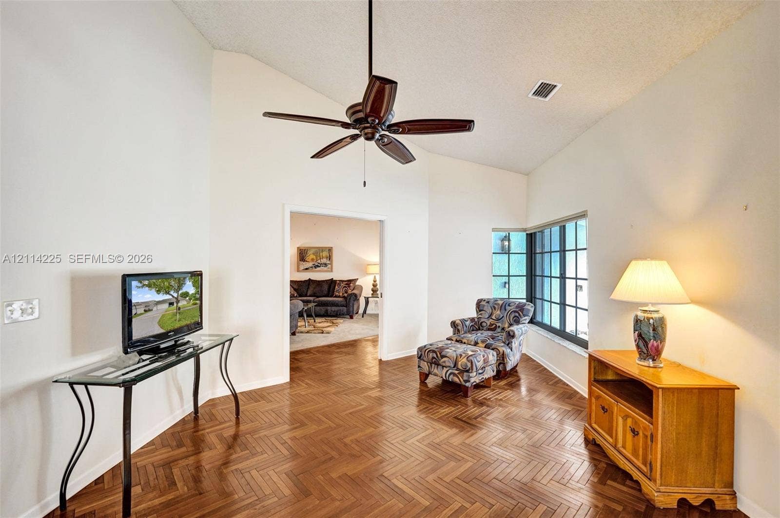 5741 SW 88th Terrace, Cooper City, FL 33328 Vaulted ceilings featuring a dark-finish ceiling fan, wood-finish flooring in a herringbone pattern, and multi-pane windows
