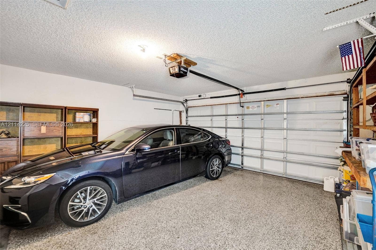 5741 SW 88th Terrace, Cooper City, FL 33328 Attached garage featuring epoxy-coated flooring, a motorized garage door opener, and built-in shelving units