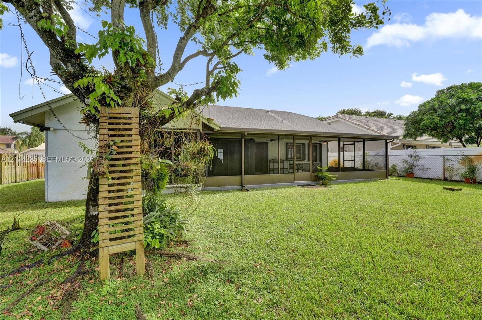 5741 SW 88th Terrace, Cooper City, FL 33328 Backyard featuring a grass lawn, screened-in porch, mature tree, and perimeter fencing