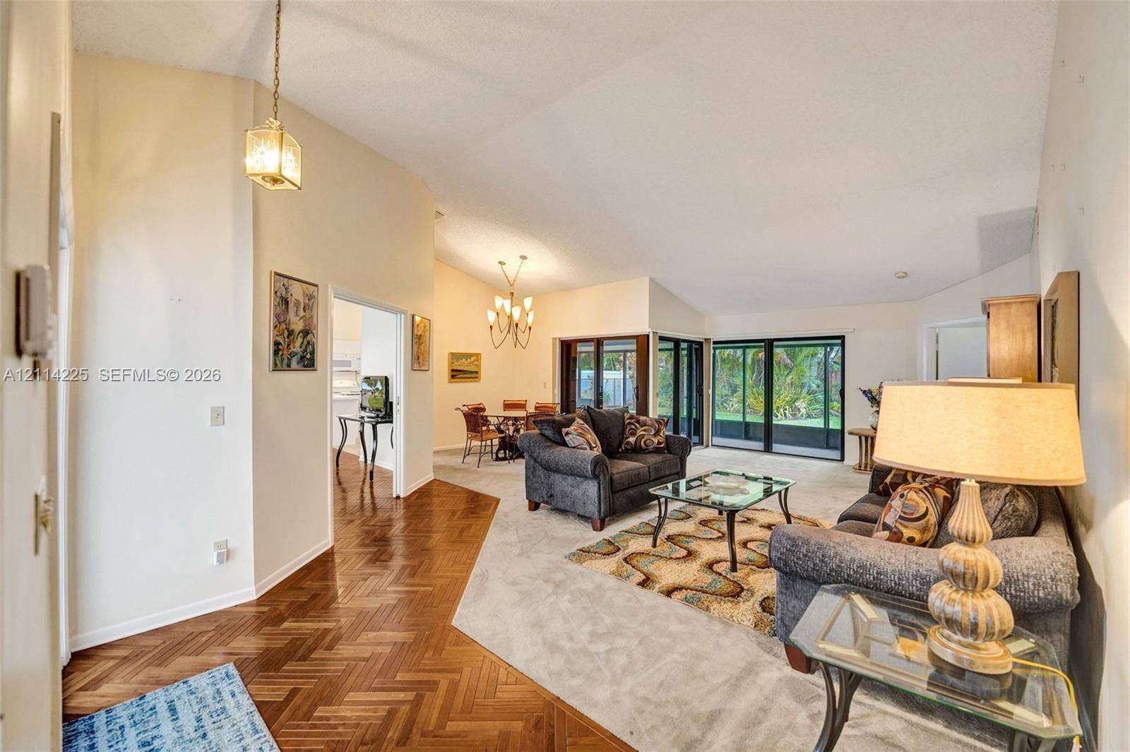 5741 SW 88th Terrace, Cooper City, FL 33328 Vaulted ceilings, herringbone-patterned wood flooring, multi-pane sliding glass doors, and dual decorative chandeliers