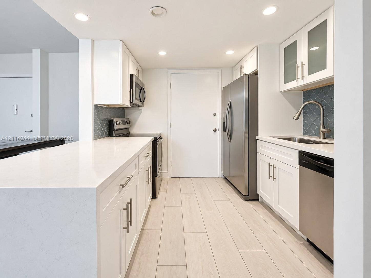 15888 SW 95th Avenue, #307, Miami, Miami, FL 33157 Kitchen featuring white shaker-style cabinetry, quartz countertops, blue geometric tile backsplash, stainless steel appliances.