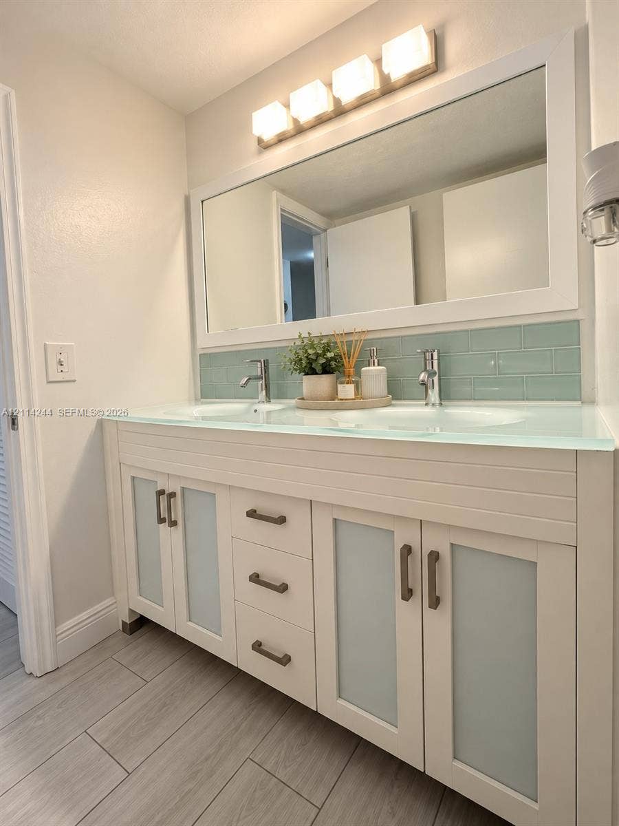 15888 SW 95th Avenue, #307, Miami, Miami, FL 33157 Double vanity featuring frosted glass cabinet doors, integrated glass countertop with dual sinks and light blue subway tile backsplash.