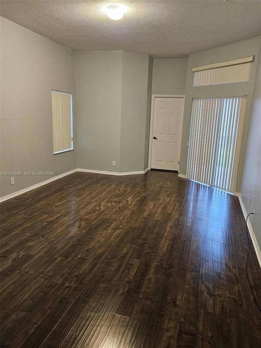 Wood-finish flooring, vaulted ceiling, sliding glass doors with transom window, and flush-mount ceiling lighting