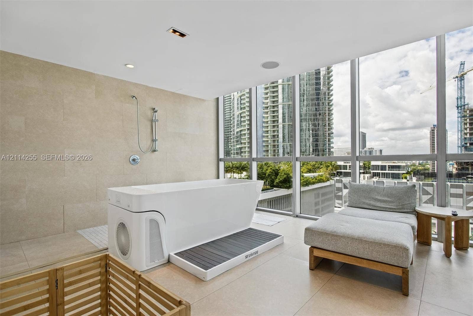 900 Biscayne Boulevard, #1705, Miami, FL 33132 Floor-to-ceiling glass windows, stone-finish wall tile, large-format tile flooring, and integrated soaking tub with handheld shower fixture