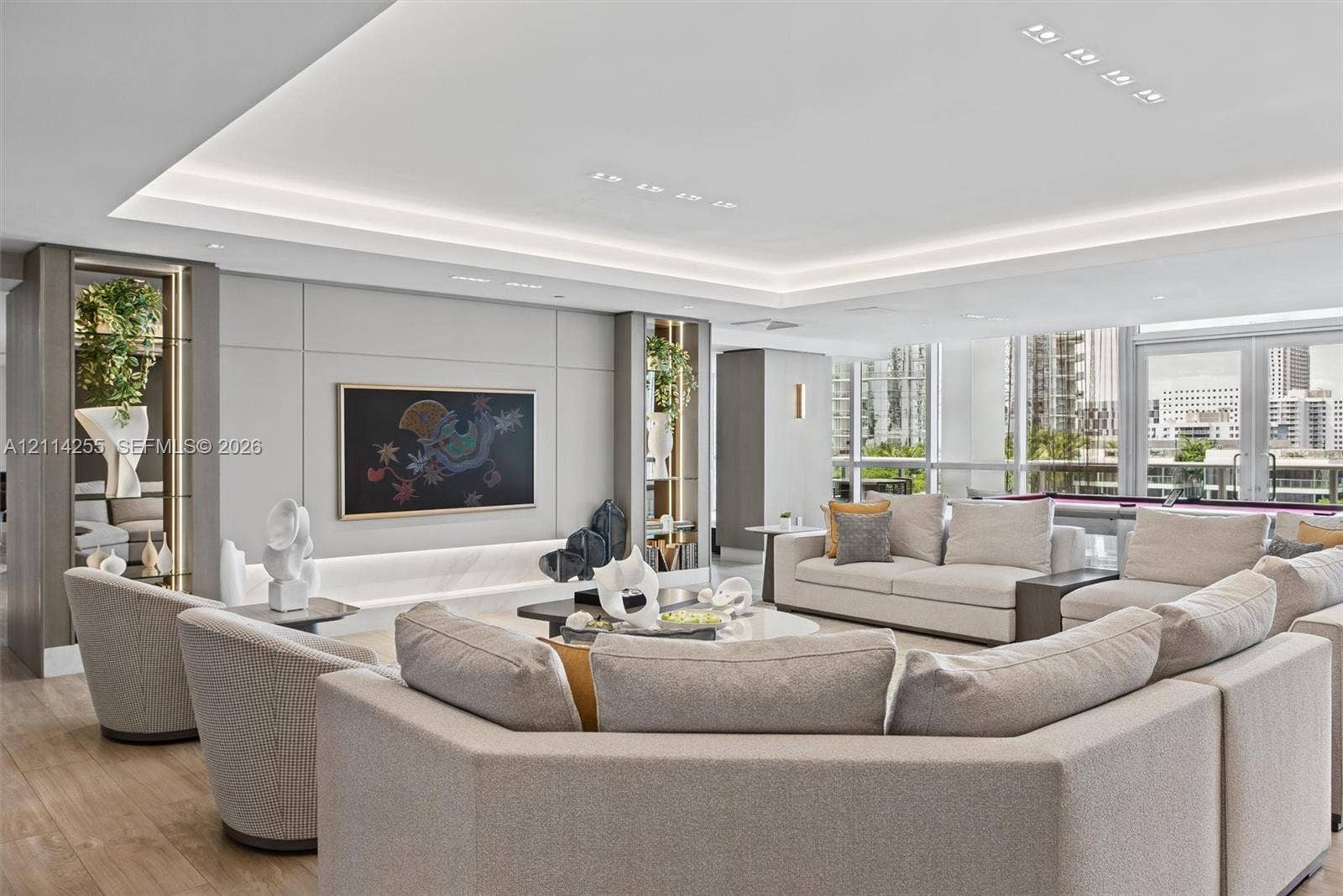 900 Biscayne Boulevard, #1705, Miami, FL 33132 Open-concept living space featuring wood-finish flooring, recessed tray ceiling with integrated cove lighting, floor-to-ceiling glass windows, and built-in shelving units with recessed lighting