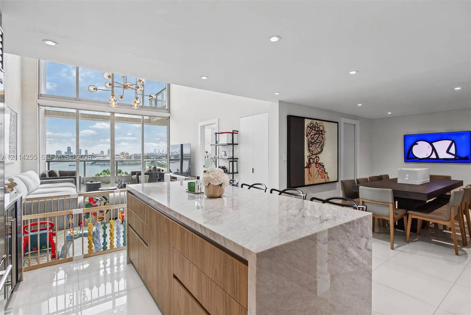 900 Biscayne Boulevard, #1705, Miami, FL 33132 Kitchen island with stone countertop and waterfall edge, flat-panel wood-finish cabinetry, floor-to-ceiling windows, recessed lighting, and large-format tile flooring
