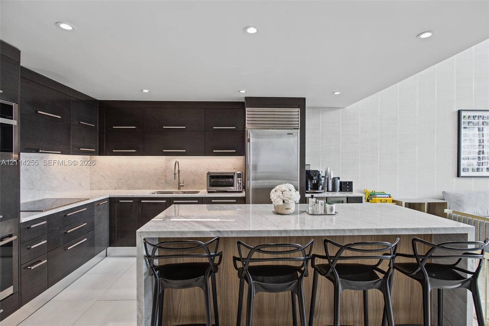 900 Biscayne Boulevard, #1705, Miami, FL 33132 Kitchen featuring dark wood-finish cabinetry, a waterfall-edge stone island, under-cabinet lighting, stainless steel appliances, and large-format tile flooring