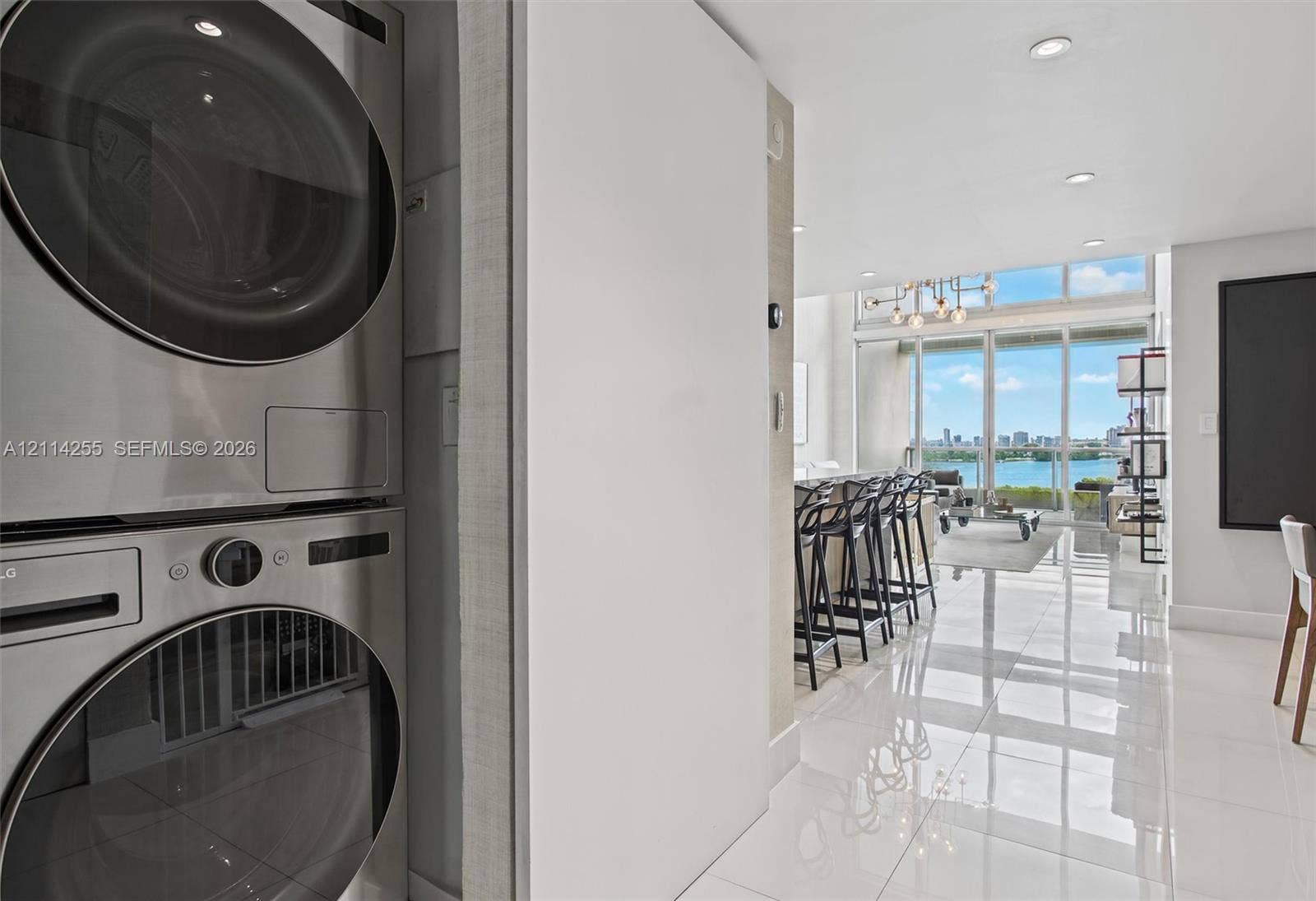 900 Biscayne Boulevard, #1705, Miami, FL 33132 Stacked stainless steel laundry appliances, polished tile flooring, recessed ceiling lighting, and floor-to-ceiling glass paneling