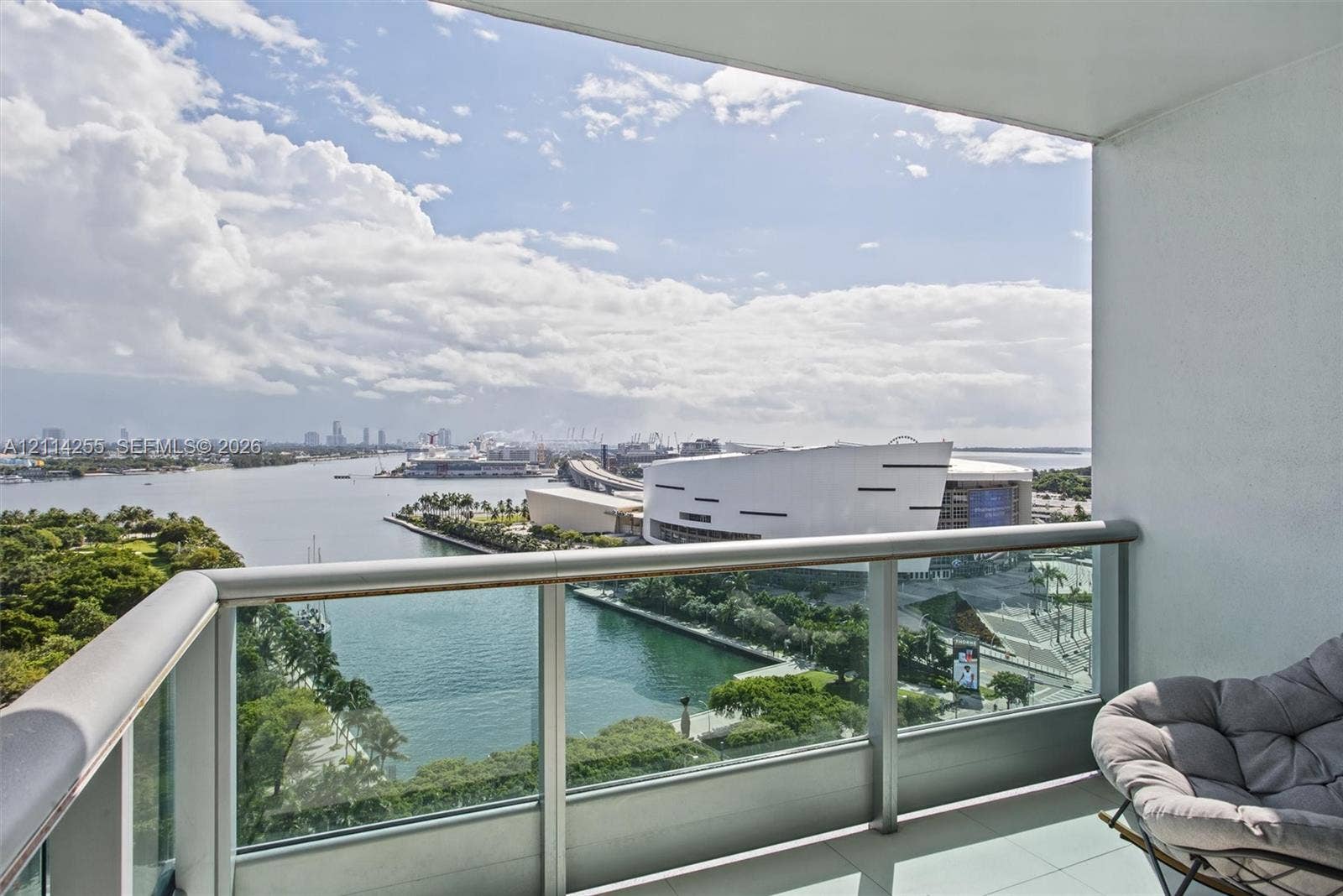 900 Biscayne Boulevard, #1705, Miami, FL 33132 Covered balcony featuring a glass panel railing, metal frame, and tile flooring, oriented toward a water and city skyline horizon