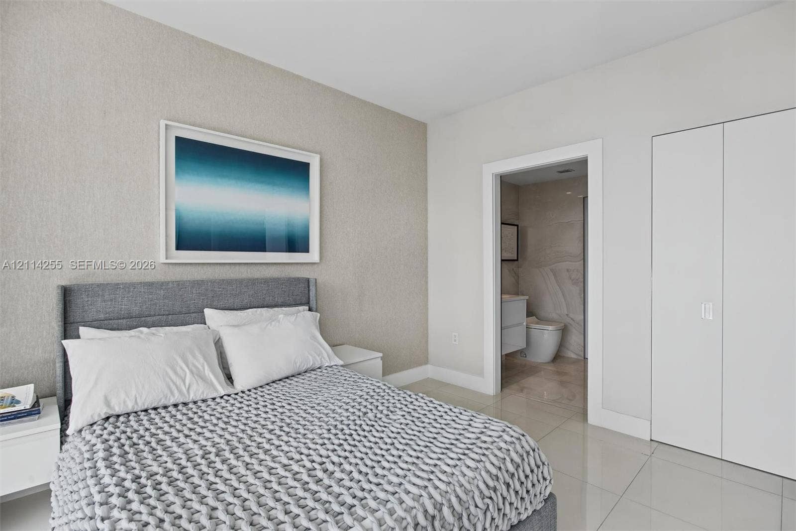 900 Biscayne Boulevard, #1705, Miami, FL 33132 Neutral-toned textured accent wall featuring smooth-finish flooring, minimalist double-door closet cabinetry, and a clean-lined interior doorway
