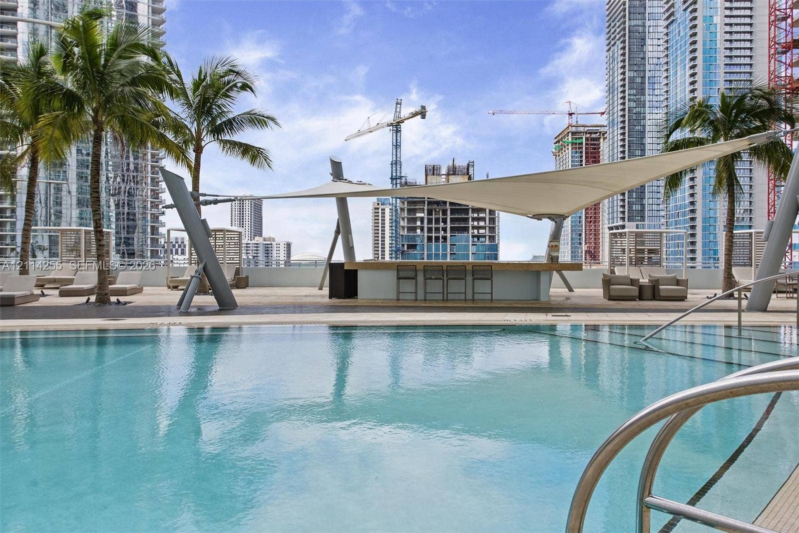 900 Biscayne Boulevard, #1705, Miami, FL 33132 Swimming pool with a stainless steel ladder entry, paved deck, and a built-in bar sheltered by a tensile shade structure