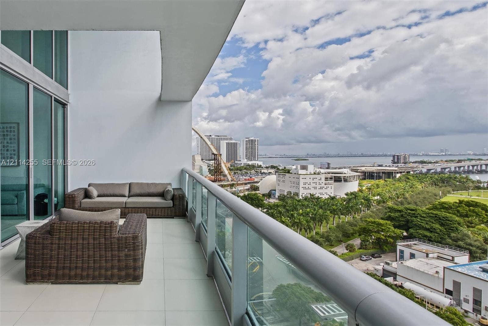 900 Biscayne Boulevard, #1705, Miami, FL 33132 Covered balcony with large-format tile flooring, floor-to-ceiling glass sliding doors, and a glass-paneled railing