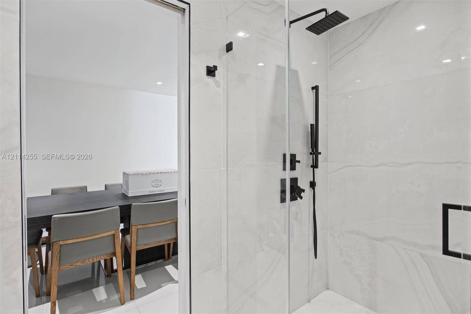 900 Biscayne Boulevard, #1705, Miami, FL 33132 Walk-in shower featuring large-format stone-finish tile, glass enclosure, matte black rainfall showerhead, and matching handheld sprayer
