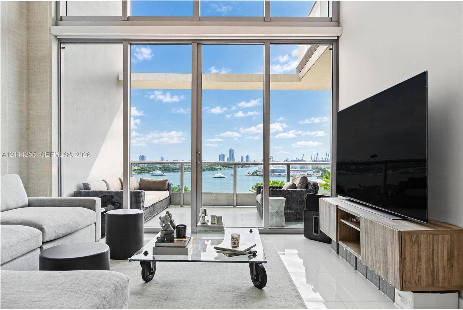 900 Biscayne Boulevard, #1705, Miami, FL 33132 Floor-to-ceiling windows, soaring double-height ceilings, tiled flooring, and a glass-paneled balcony featuring water and cityscape scenery