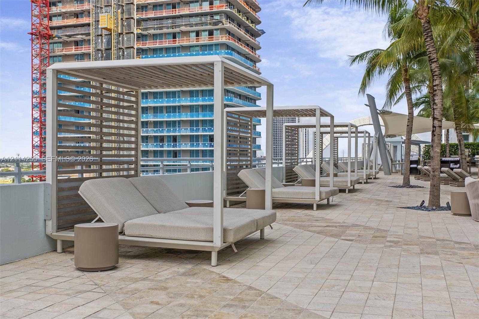 900 Biscayne Boulevard, #1705, Miami, FL 33132 Outdoor terrace featuring light-toned stone tile flooring, structural metal cabanas with slat-wall detailing, and mature palm trees