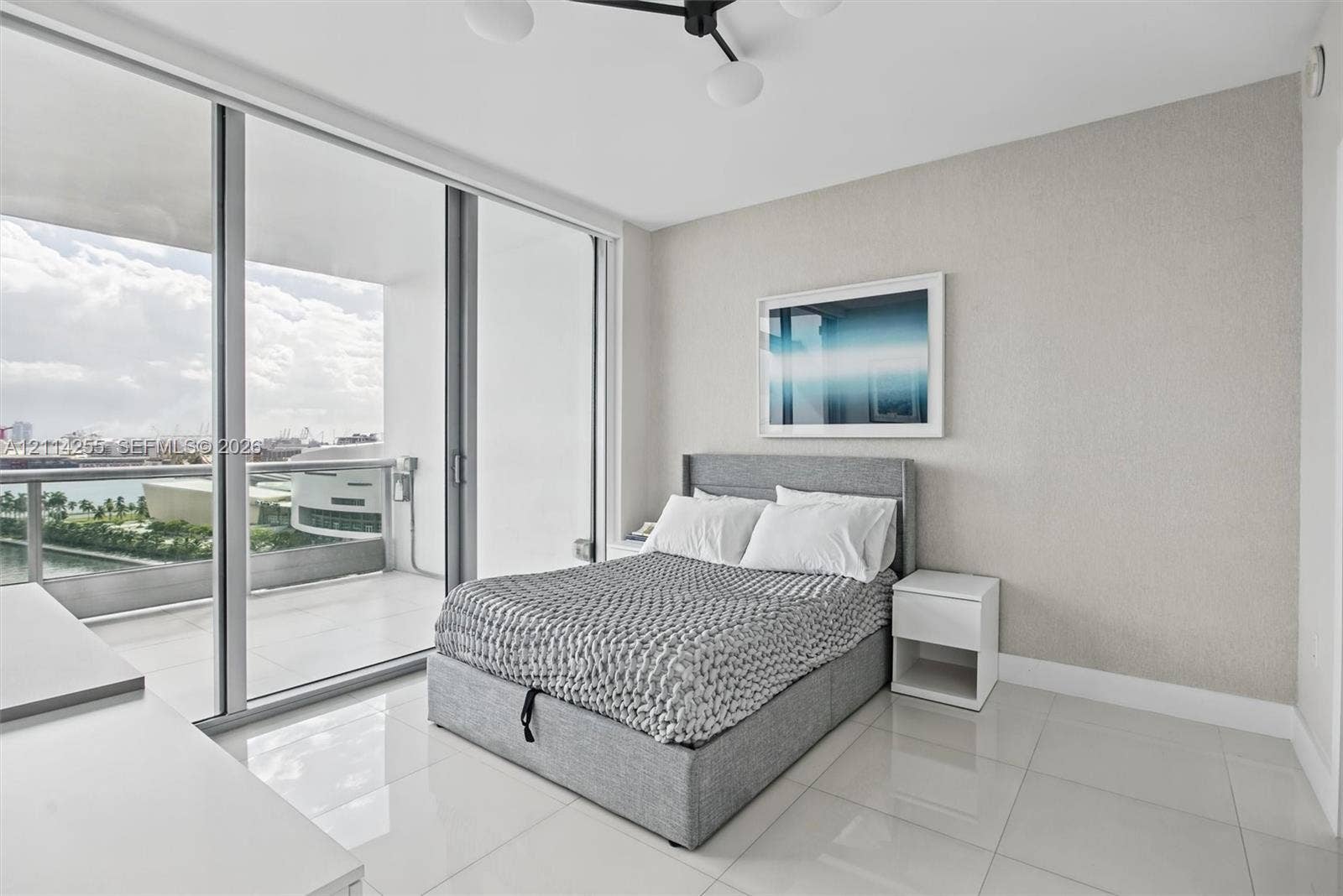 900 Biscayne Boulevard, #1705, Miami, FL 33132 Floor-to-ceiling glass sliding doors, private balcony, neutral wall finish, light-colored tile flooring, and contemporary multi-arm overhead light fixture