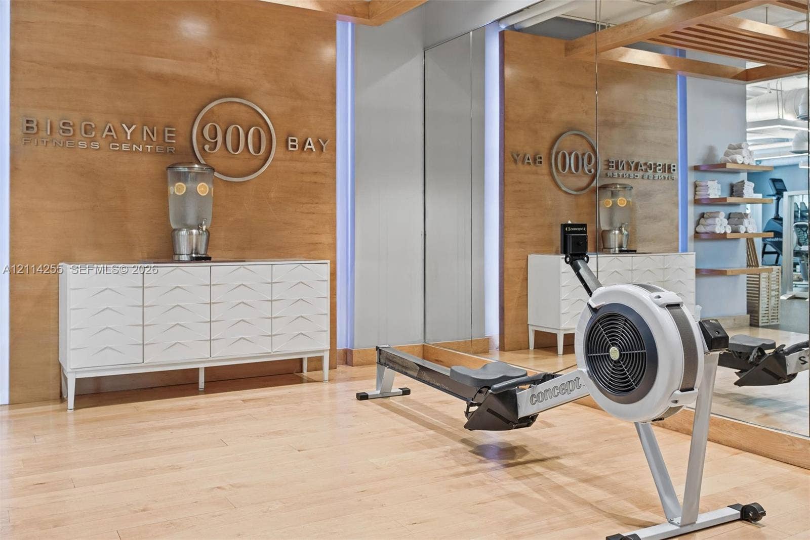 900 Biscayne Boulevard, #1705, Miami, FL 33132 Fitness center featuring wood-panel wall accents, full-height wall mirrors, built-in recessed shelving, and wood-finish flooring