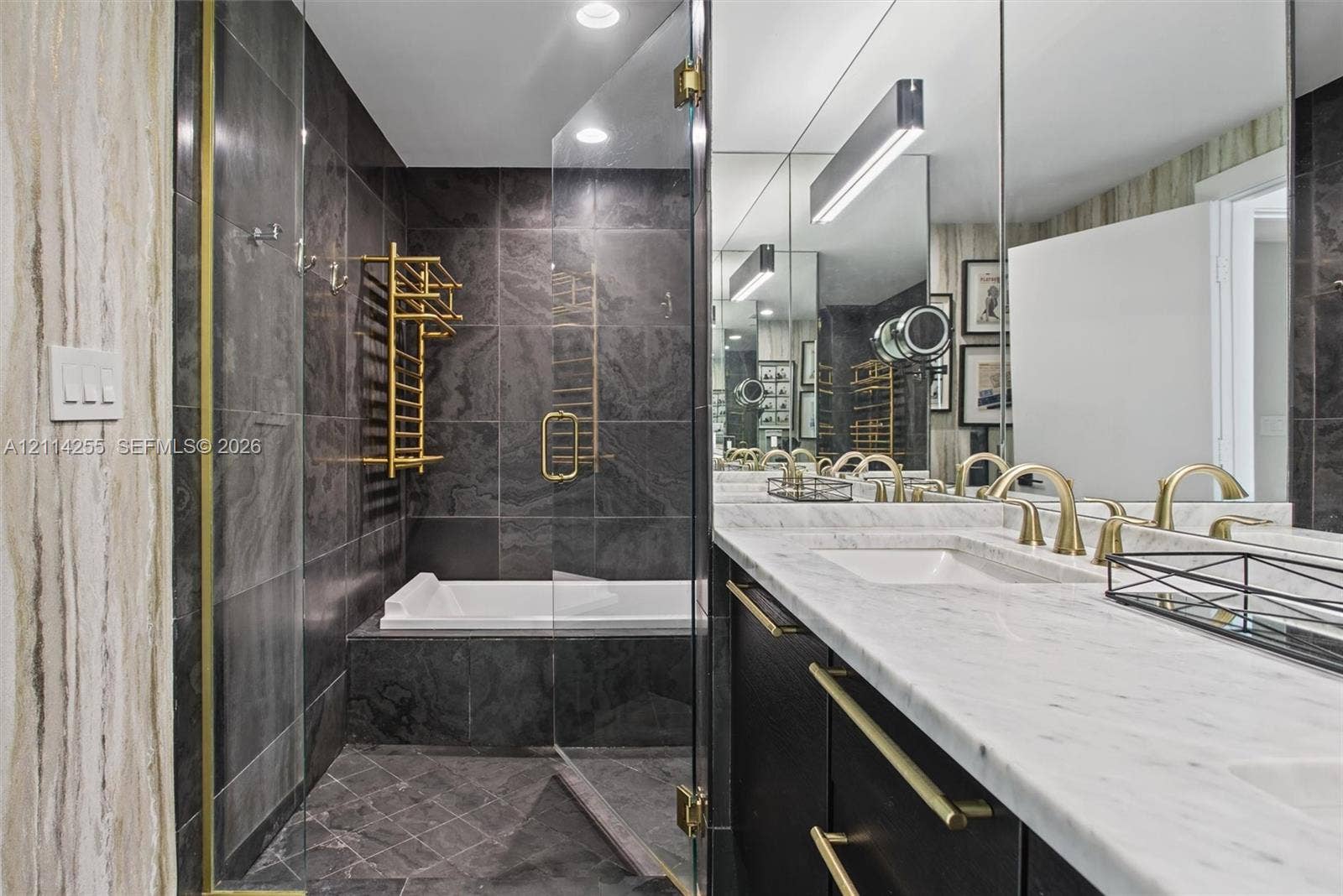 900 Biscayne Boulevard, #1705, Miami, FL 33132 Bathroom featuring a double vanity with stone countertops, dark cabinetry with gold-tone hardware, a glass-enclosed shower, and a built-in tub with wall-mounted gold-tone towel warmer