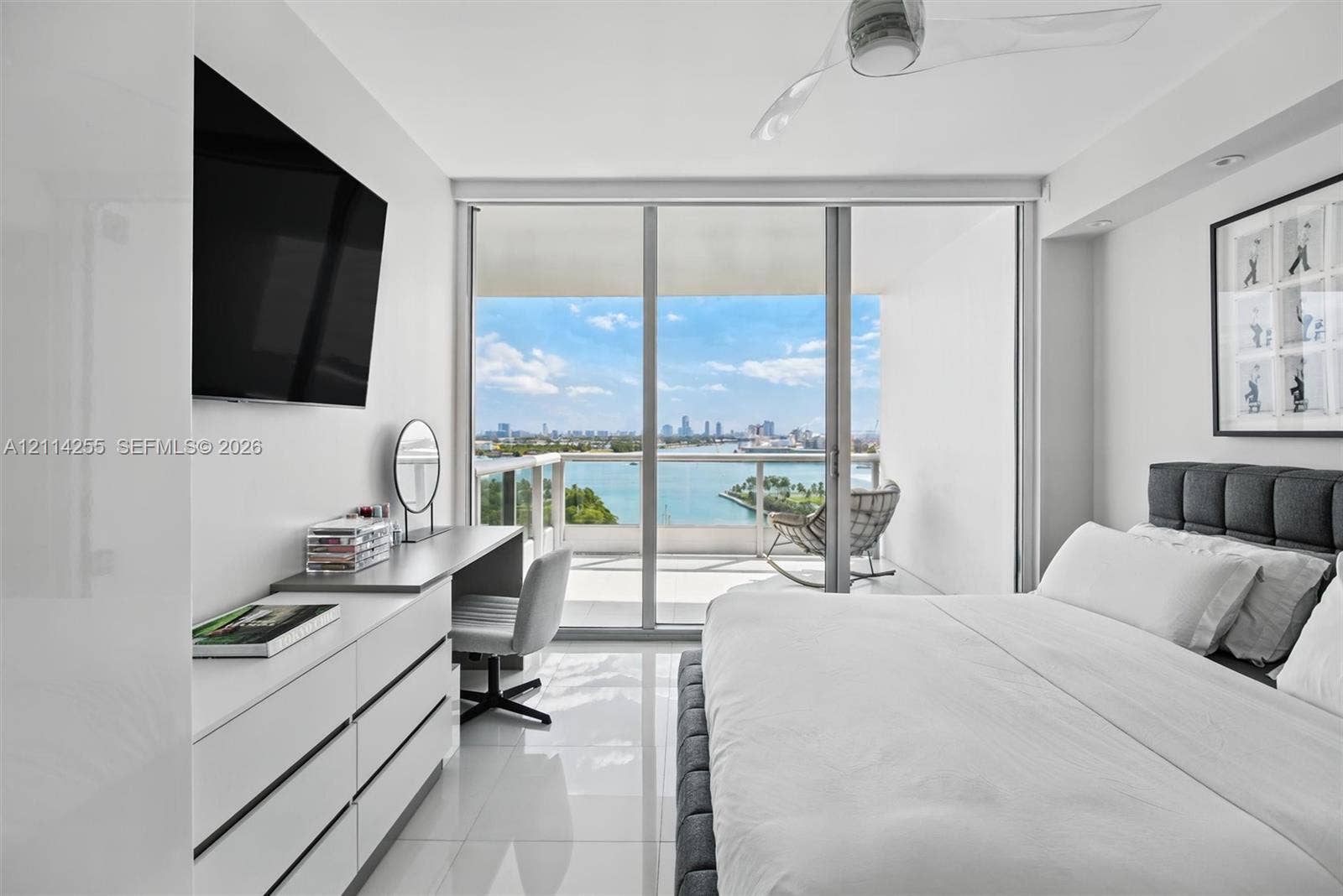 900 Biscayne Boulevard, #1705, Miami, FL 33132 Floor-to-ceiling sliding glass doors, white tile flooring, recessed ceiling lighting, three-blade ceiling fan, and private balcony with water and city skyline backdrop
