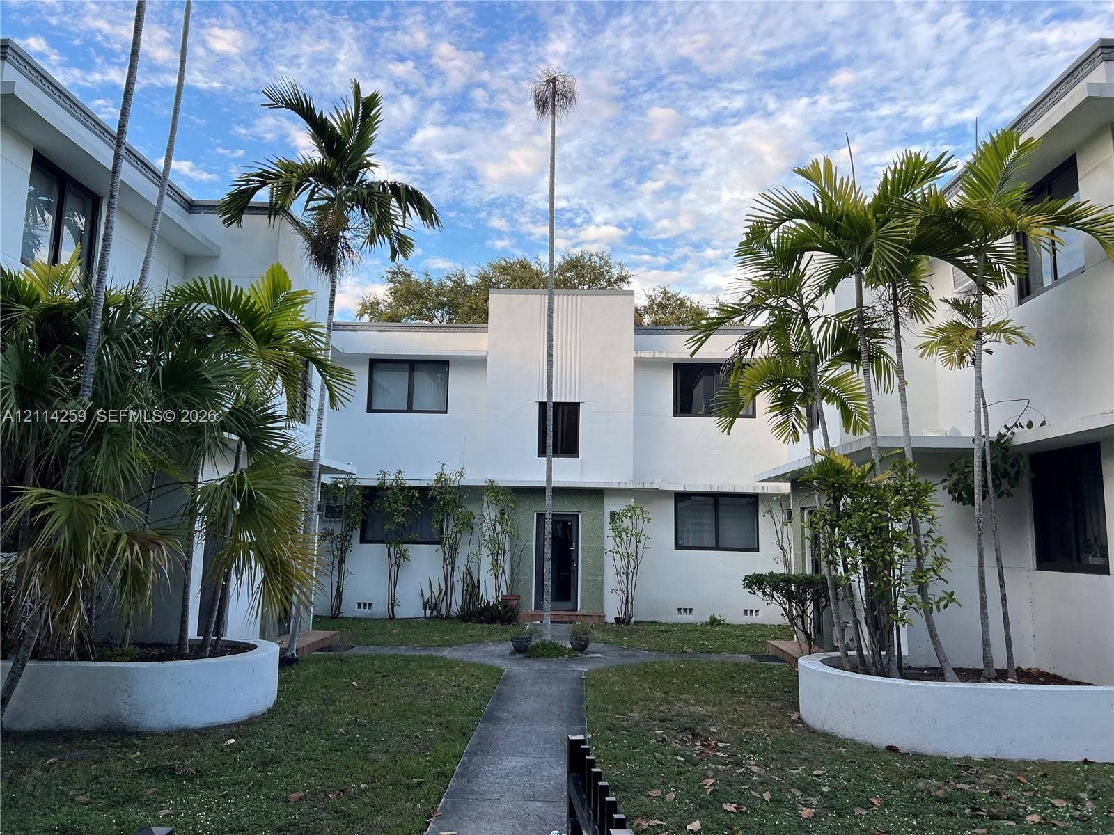 1895 SW 22nd, #5, Miami, Miami, FL 33145 Multi-story stucco exterior featuring a central courtyard with palm trees, concrete pathways, and raised circular planting beds