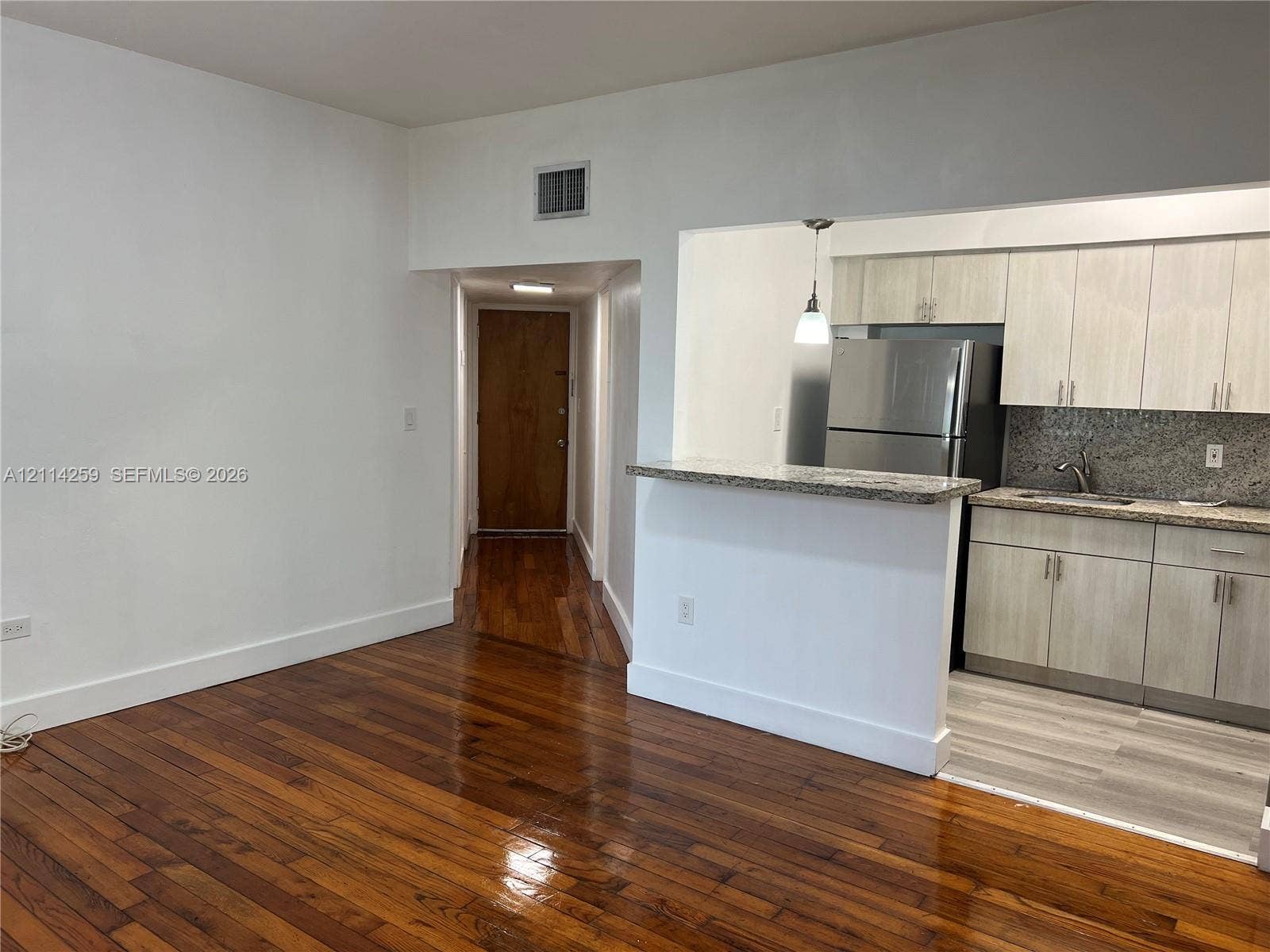 1895 SW 22nd, #5, Miami, Miami, FL 33145 Hardwood flooring, kitchen featuring light-toned cabinetry, stone-finish countertops, stainless steel refrigerator, and breakfast bar