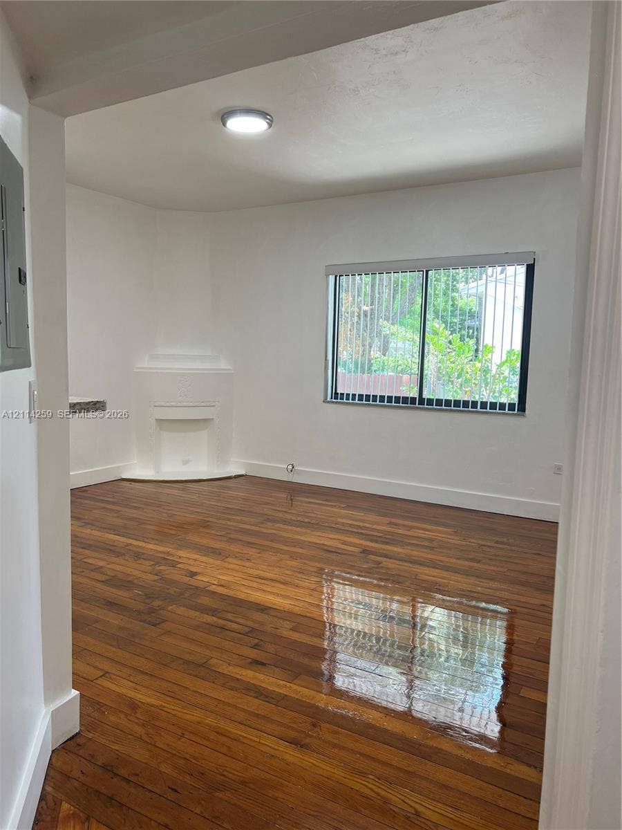 1895 SW 22nd, #5, Miami, Miami, FL 33145 Interior space featuring wood-finish flooring, a corner fireplace mantel, a dual-pane horizontal sliding window, and flush-mount ceiling lighting