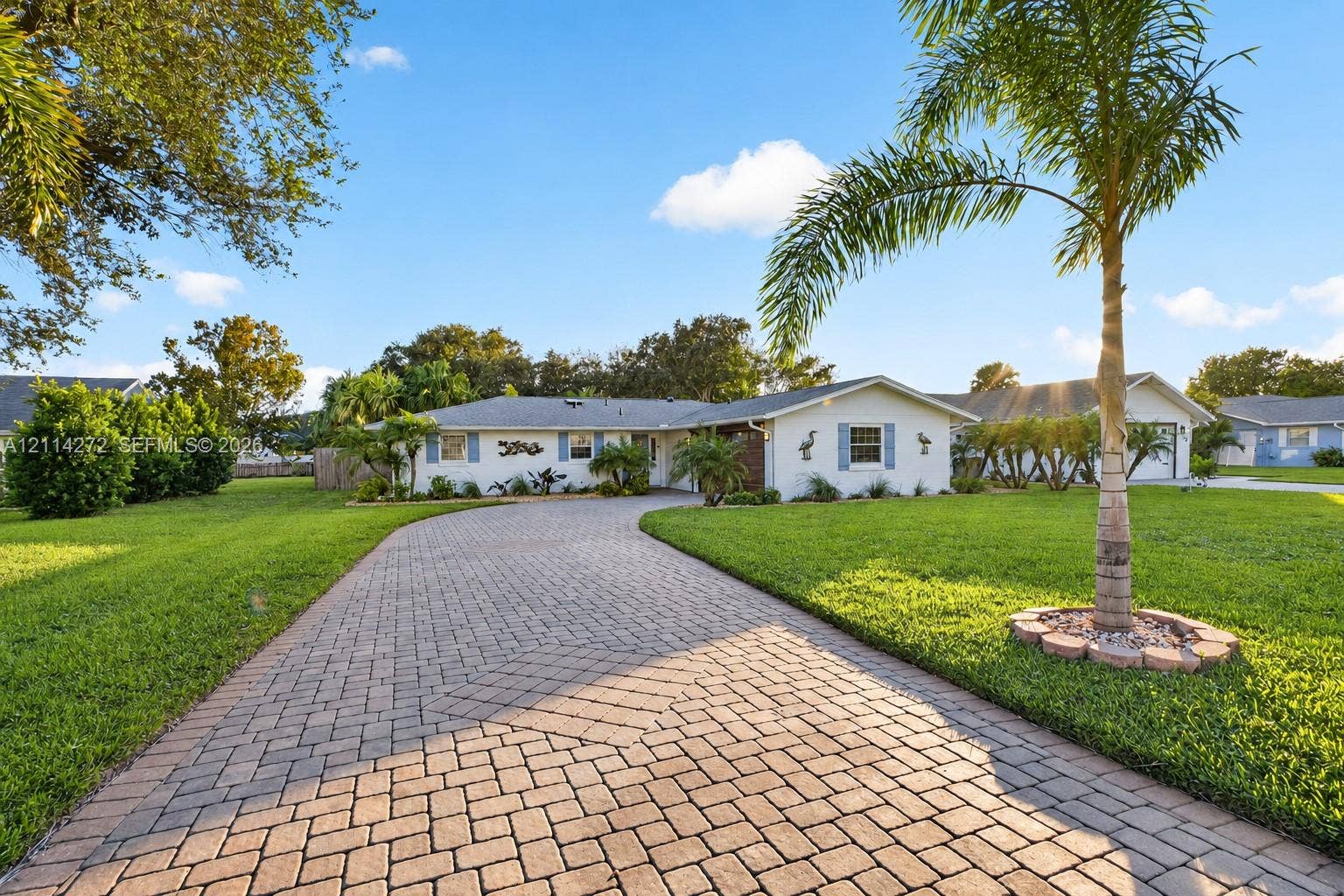 110 Cunningham, New Smyrna Beach, FL 32168 Single-story residence featuring a paved stone driveway, manicured lawn, and mature palm landscaping