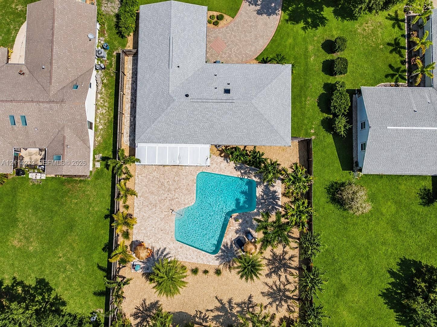 110 Cunningham, New Smyrna Beach, FL 32168 Aerial perspective of a property featuring an in-ground swimming pool, stone-paver pool deck, covered patio, manicured lawn, and paved circular driveway