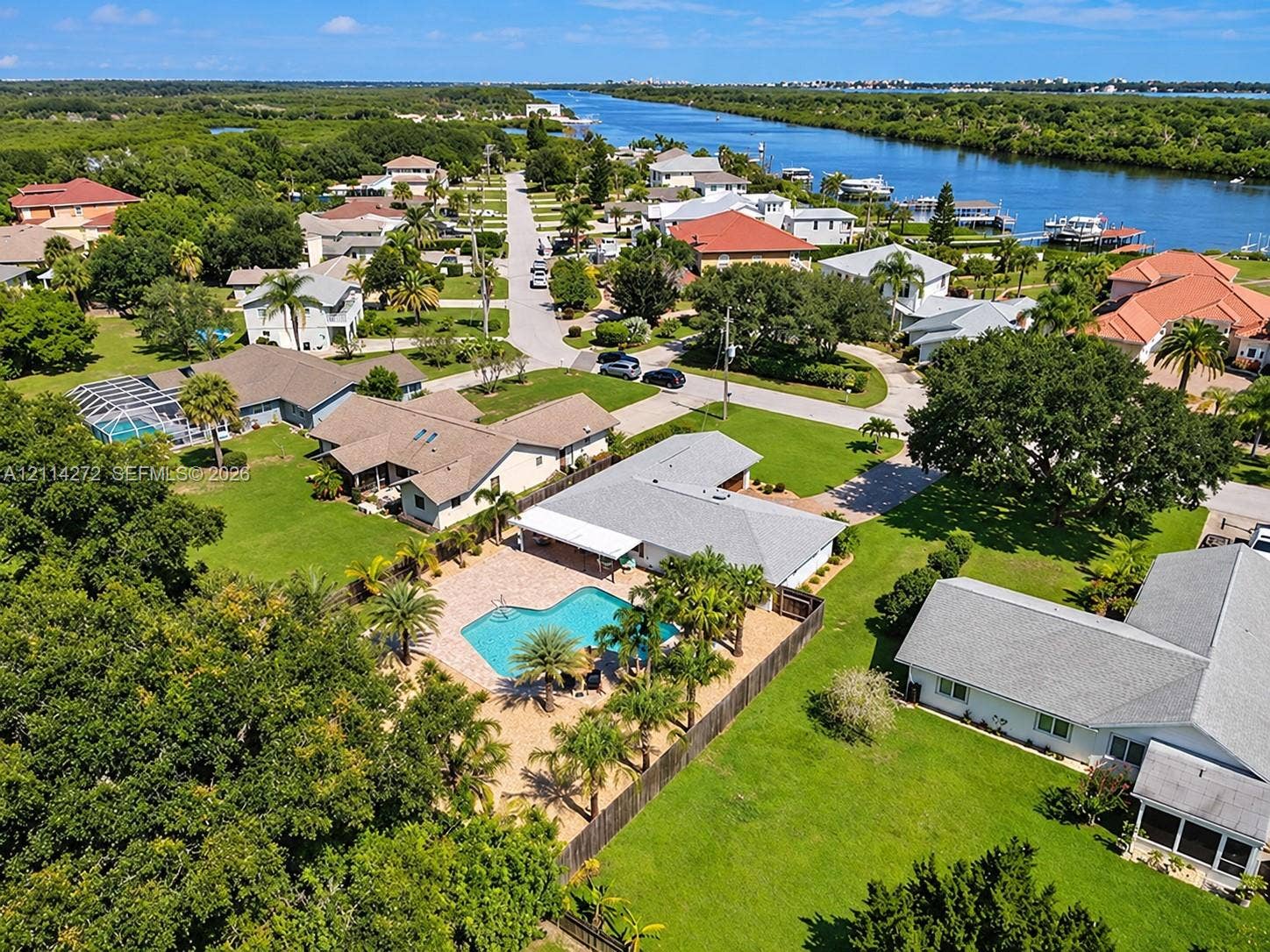 110 Cunningham, New Smyrna Beach, FL 32168 Aerial perspective featuring a single-story residence with a paved pool deck, custom-shaped swimming pool, mature palm trees, and expansive lawn area