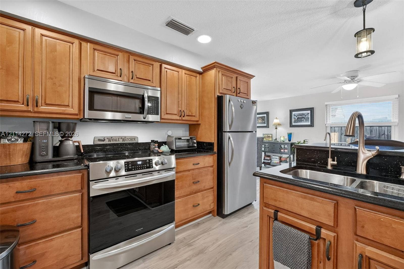 110 Cunningham, New Smyrna Beach, FL 32168 Kitchen featuring natural wood cabinetry, dark stone countertops, stainless steel appliances, a dual-basin undermount sink with a gooseneck faucet, and wood-finish flooring