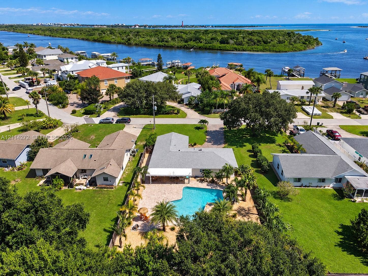 110 Cunningham, New Smyrna Beach, FL 32168 Aerial perspective of a single-story residence featuring a concrete-tile roof, an expansive paved patio, a private in-ground swimming pool, and established landscaping