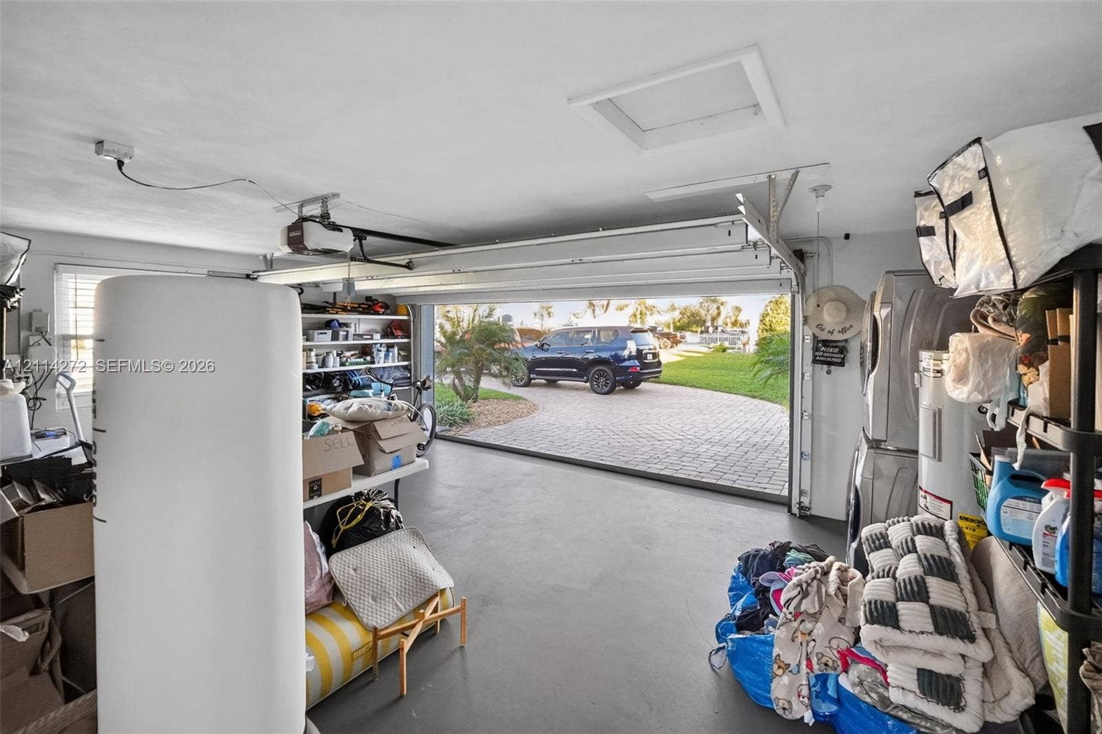 110 Cunningham, New Smyrna Beach, FL 32168 Enclosed garage featuring a concrete floor, built-in shelving, and an overhead automatic garage door opener