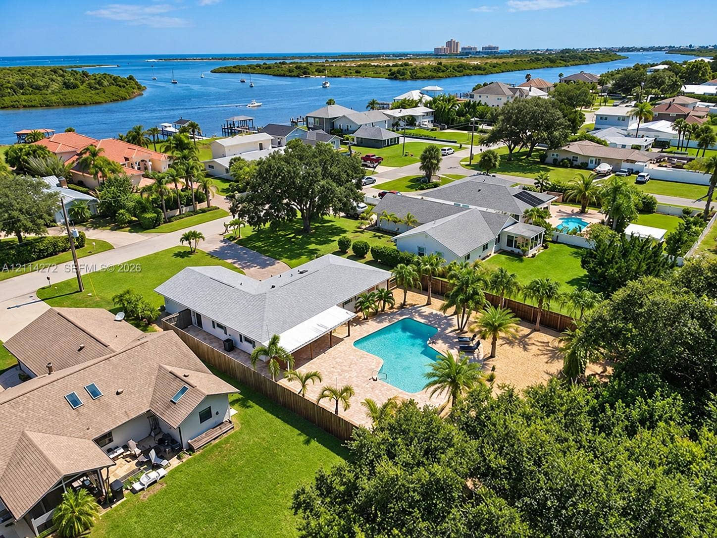 110 Cunningham, New Smyrna Beach, FL 32168 Aerial perspective of a property featuring an in-ground swimming pool, stone-paver pool deck, palm landscaping, and privacy fencing