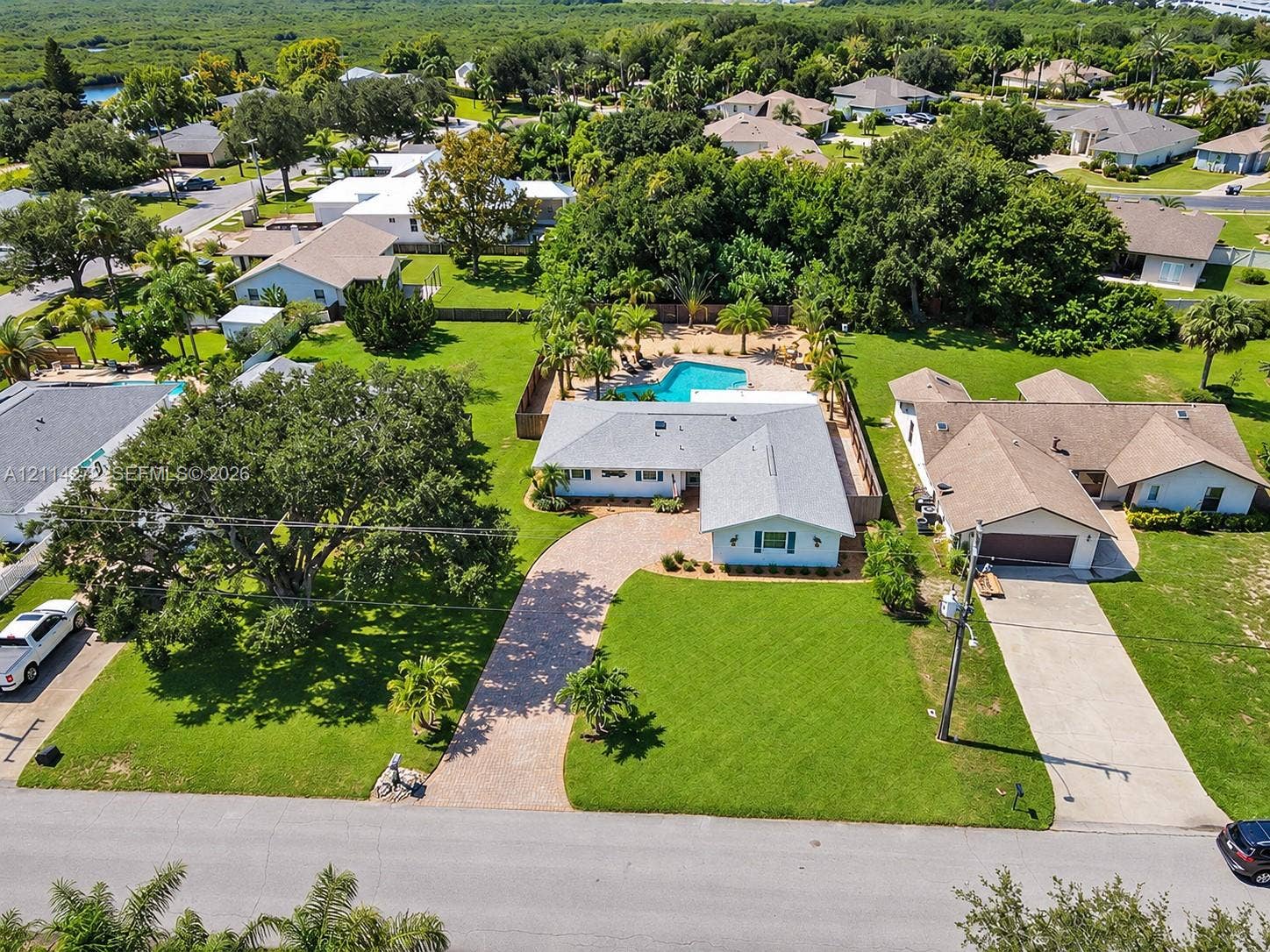 110 Cunningham, New Smyrna Beach, FL 32168 Single-story residence featuring a paved circular driveway, a private in-ground swimming pool, mature perimeter landscaping, and a multi-section roofline