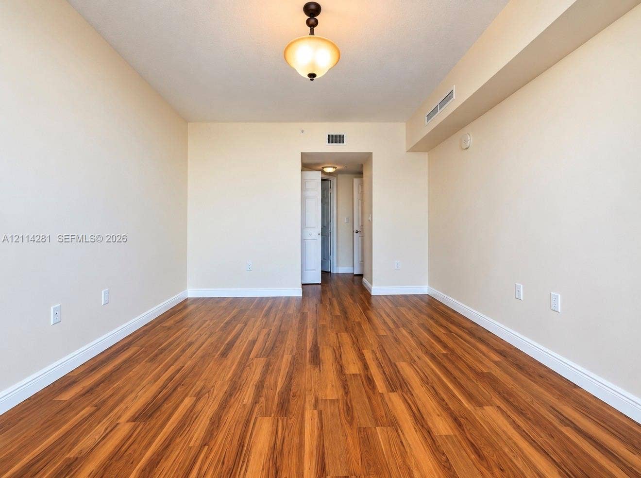 Interior space featuring wood-finish flooring, neutral wall tones, a ceiling-mounted semi-flush light fixture, and interior doors