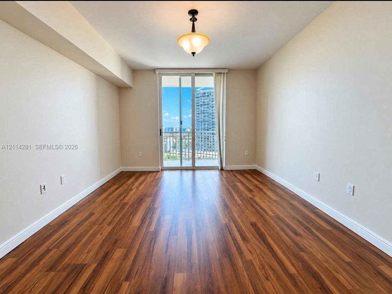 Interior room featuring wood-finish flooring, a neutral color palette, a semi-flush mount light fixture, and a sliding glass door providing access to a balcony