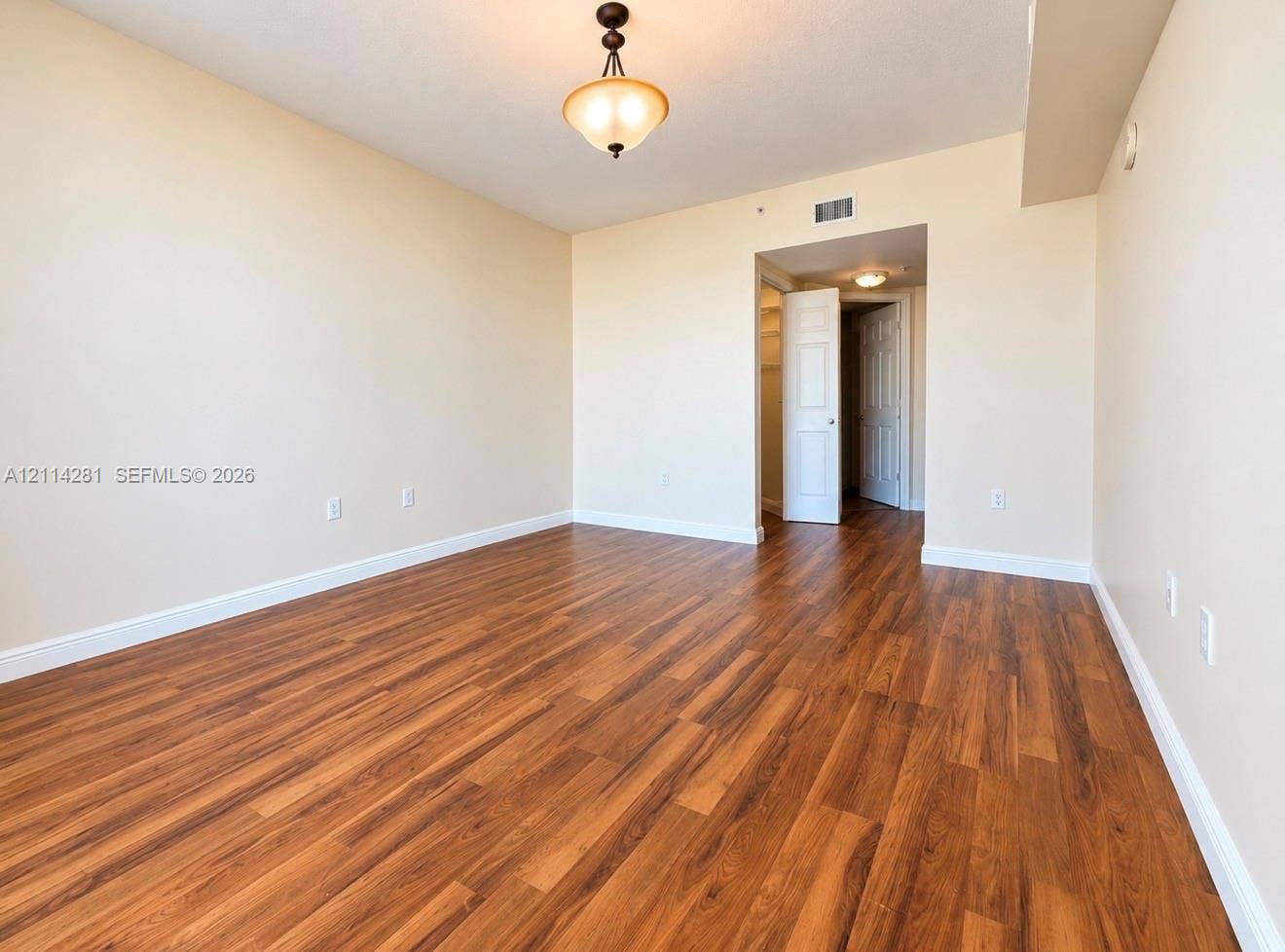 Room featuring wood-finish flooring, neutral wall paint, and a classic semi-flush mount ceiling fixture