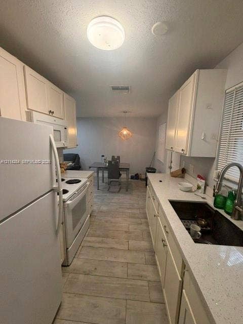 2312 Van Buren Street, #10, Hollywood, FL 33020 Kitchen featuring white shaker-style cabinetry, solid-surface countertops, wood-finish tile flooring, a stainless steel undermount sink, and a gooseneck faucet