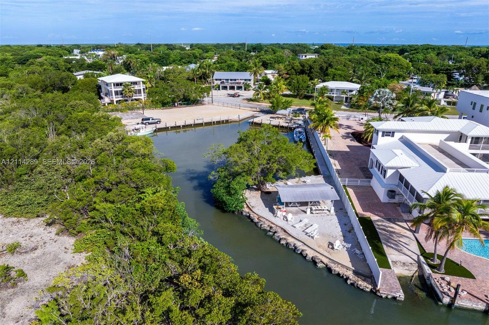 646 Cabrera Street, Key Largo, FL 33037 Waterfront property featuring a private boat dock, a covered outdoor pavilion, stone-paver hardscaping, and mature tropical landscaping