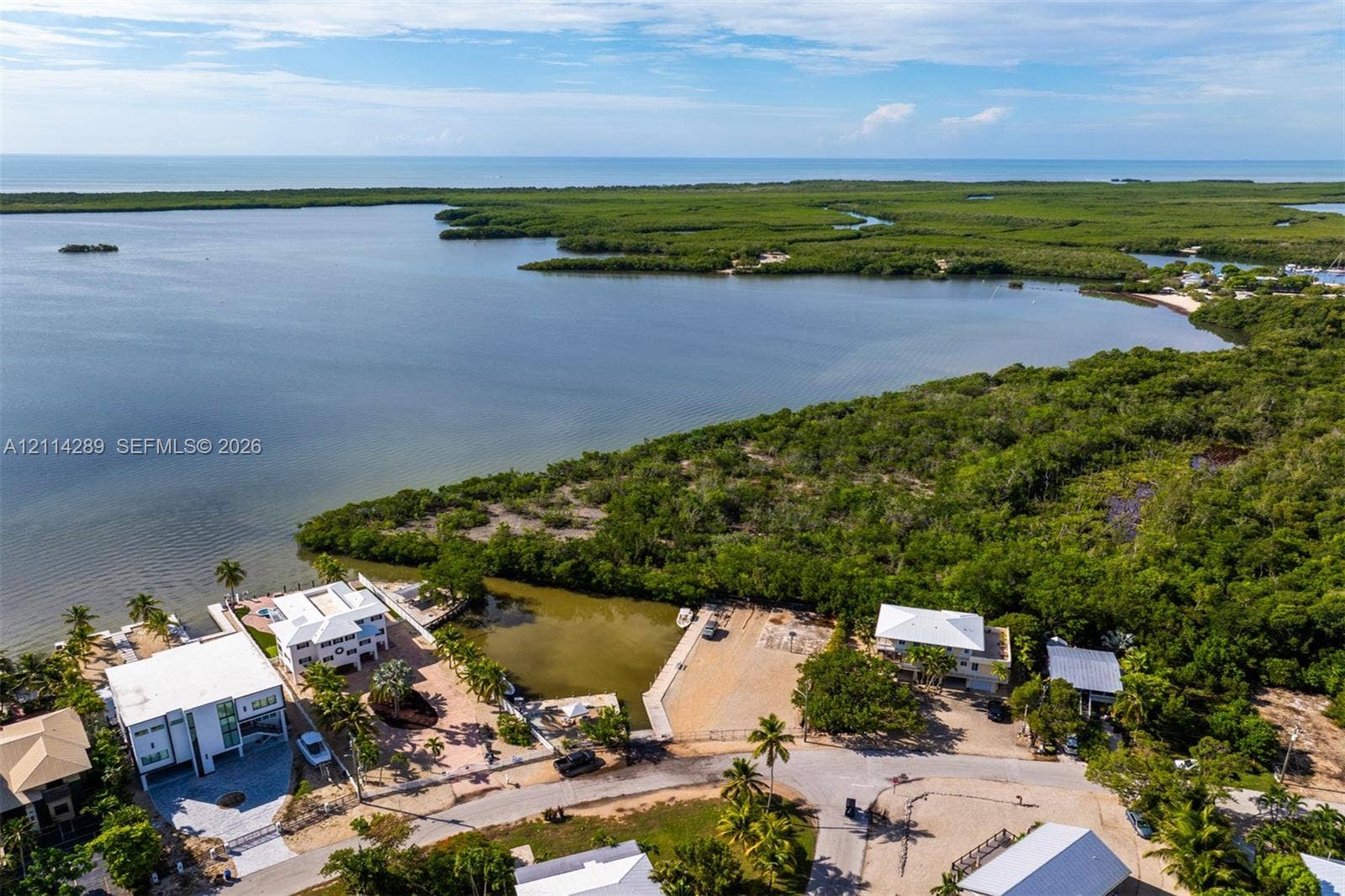 646 Cabrera Street, Key Largo, FL 33037 Waterfront property featuring a private boat slip, dock infrastructure, and direct access to coastal waterways, surrounded by native vegetation