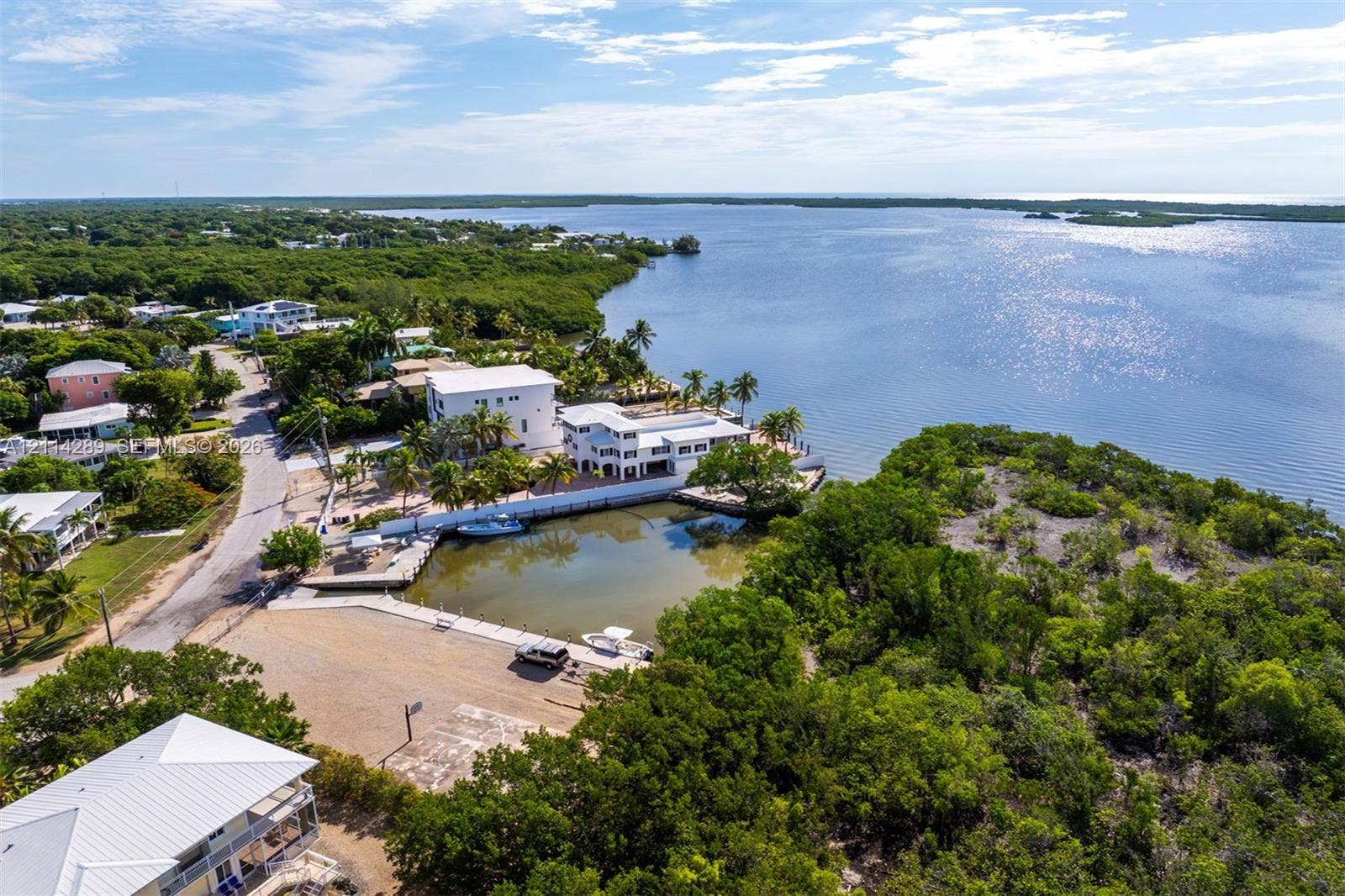 646 Cabrera Street, Key Largo, FL 33037 Waterfront property featuring a private boat basin, concrete dockage, paved driveway, and multiple stories of exterior balcony space