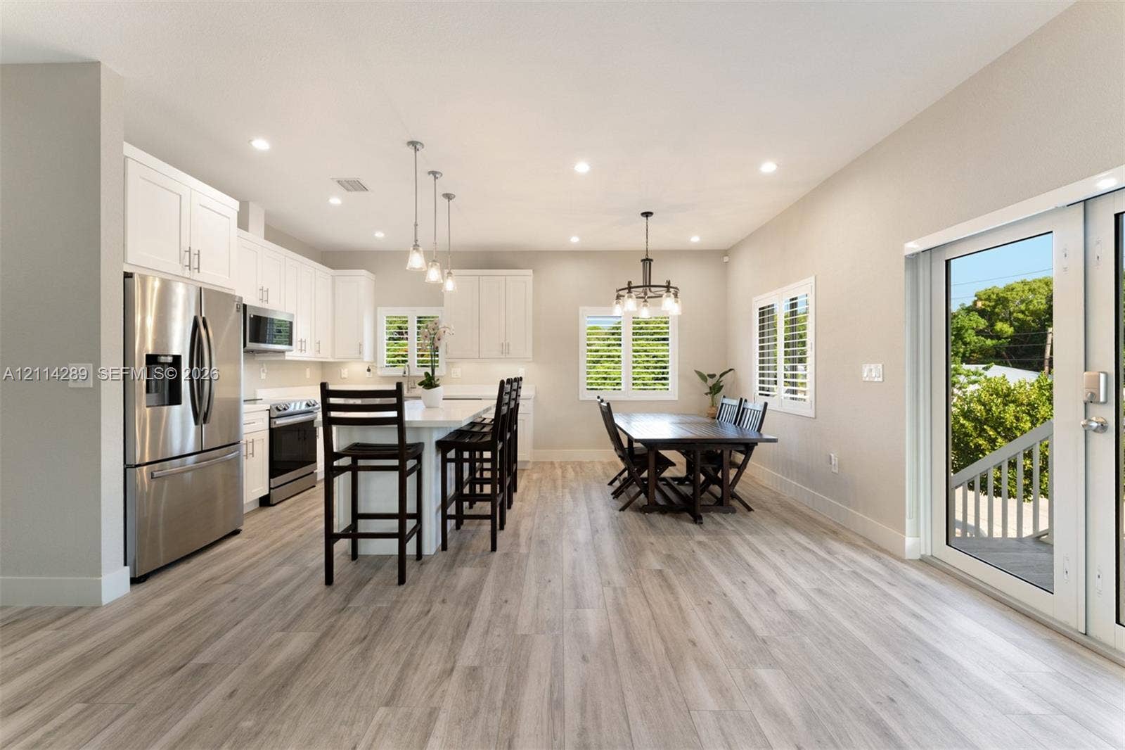646 Cabrera Street, Key Largo, FL 33037 Open-concept kitchen featuring white shaker-style cabinetry, quartz countertops, stainless steel appliances, a center island with pendant lighting, and wood-finish flooring