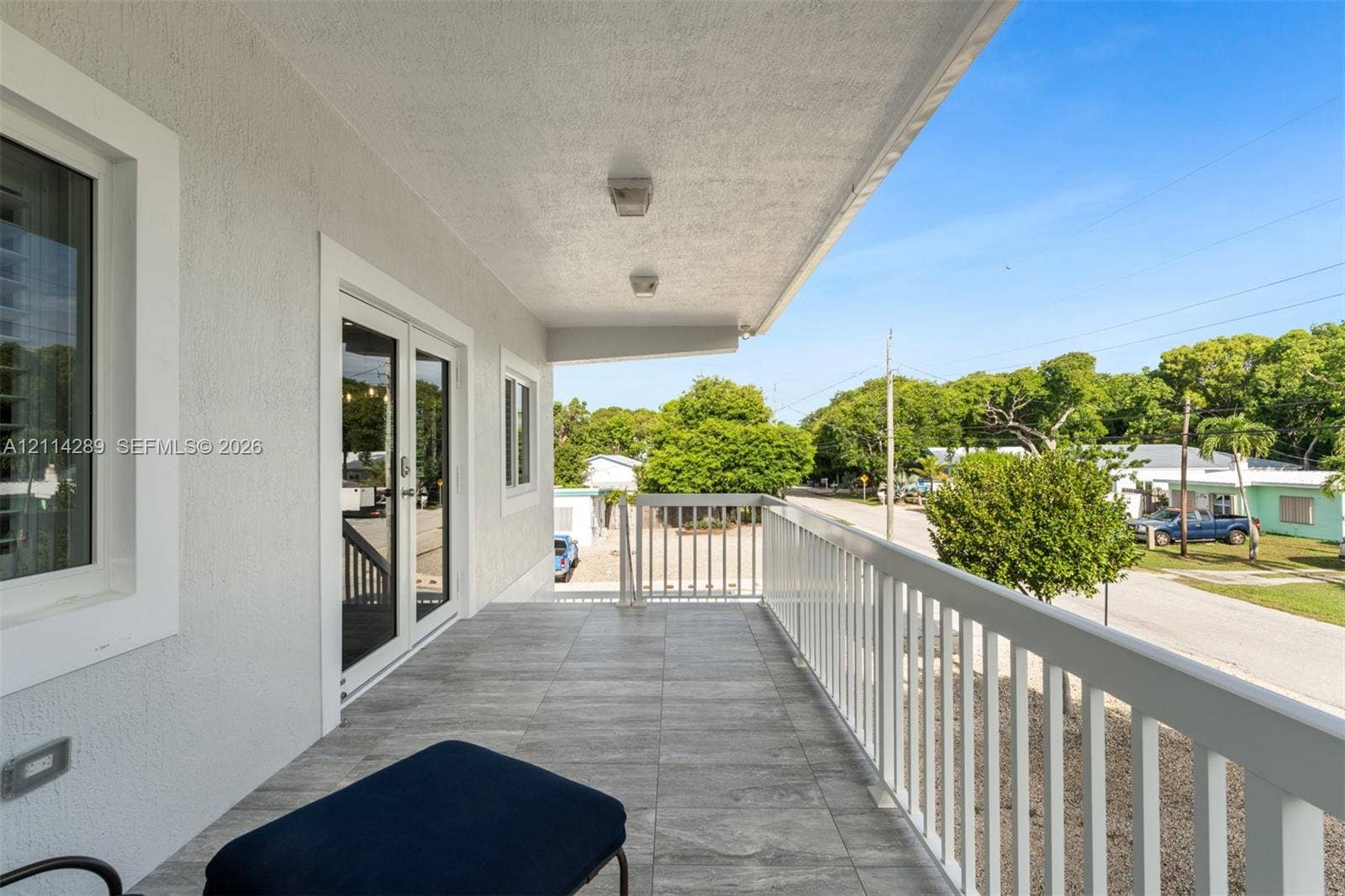 646 Cabrera Street, Key Largo, FL 33037 Covered exterior balcony featuring wood-finish tile flooring, white metal railing, recessed lighting, and double-glass door entry
